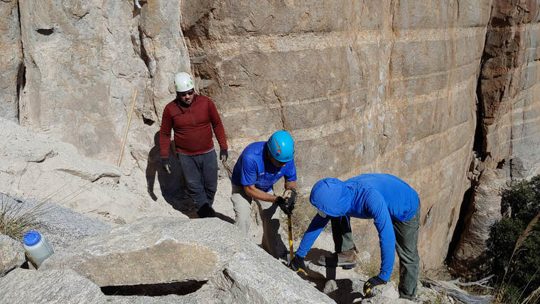 Three volunteers moving and placing rocks for belay station. Photo by Eric Ruljancich