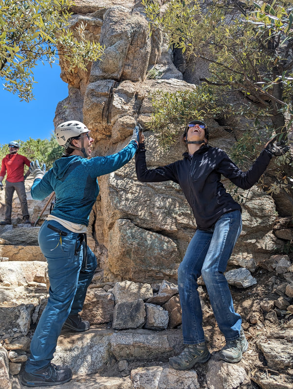 Two women high-fiving after setting rocks for a retaining wall